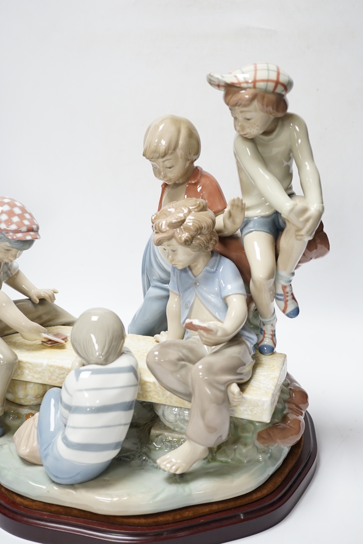 A large Nao figure group on stand of five boys sitting around a table playing cards, 33cm
